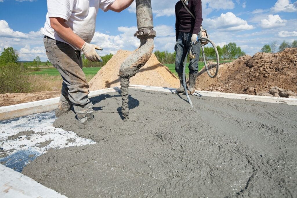 Workers pouring concrete slab at construction site