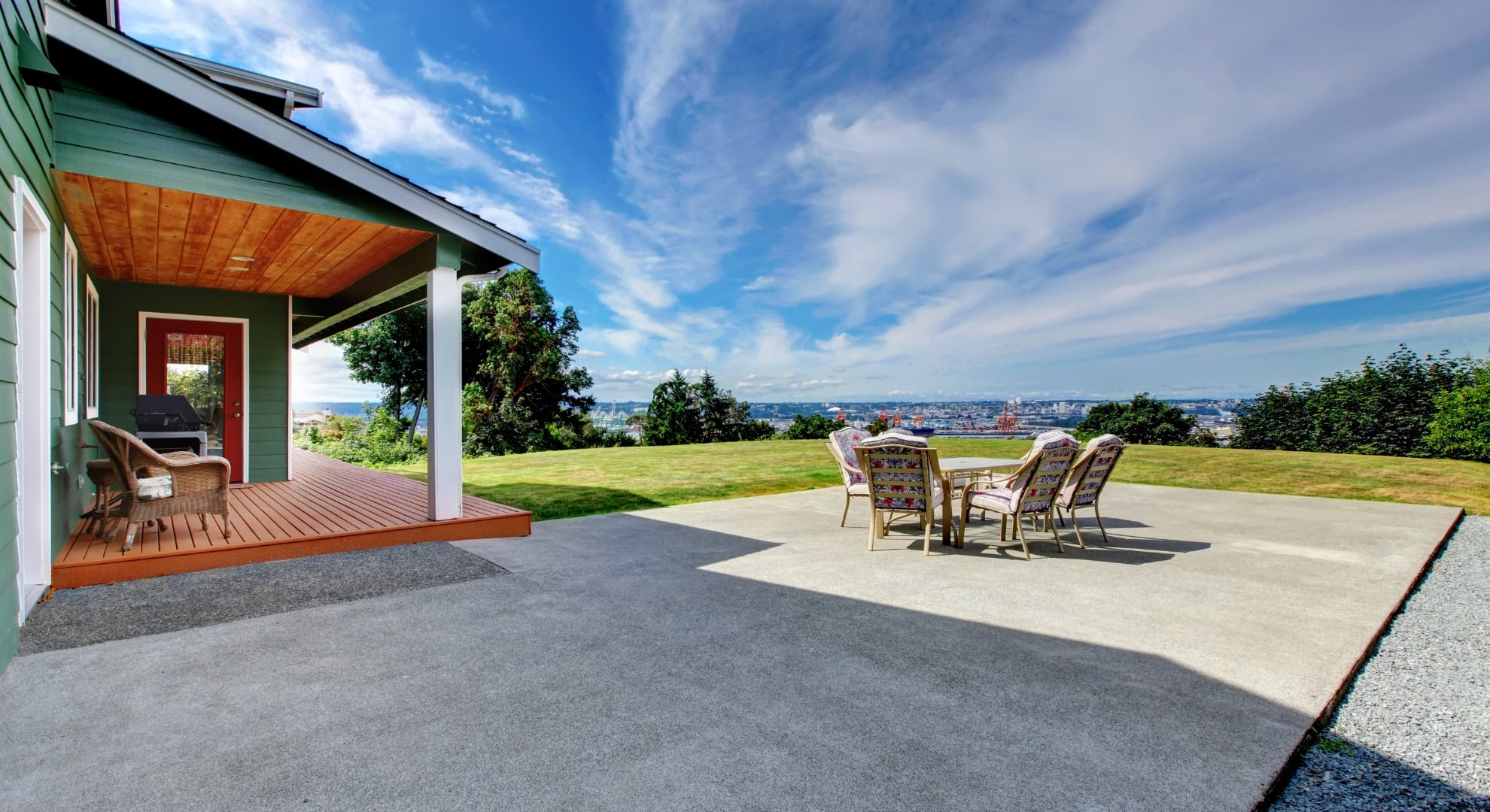 concrete patio outside the house with table and chairs