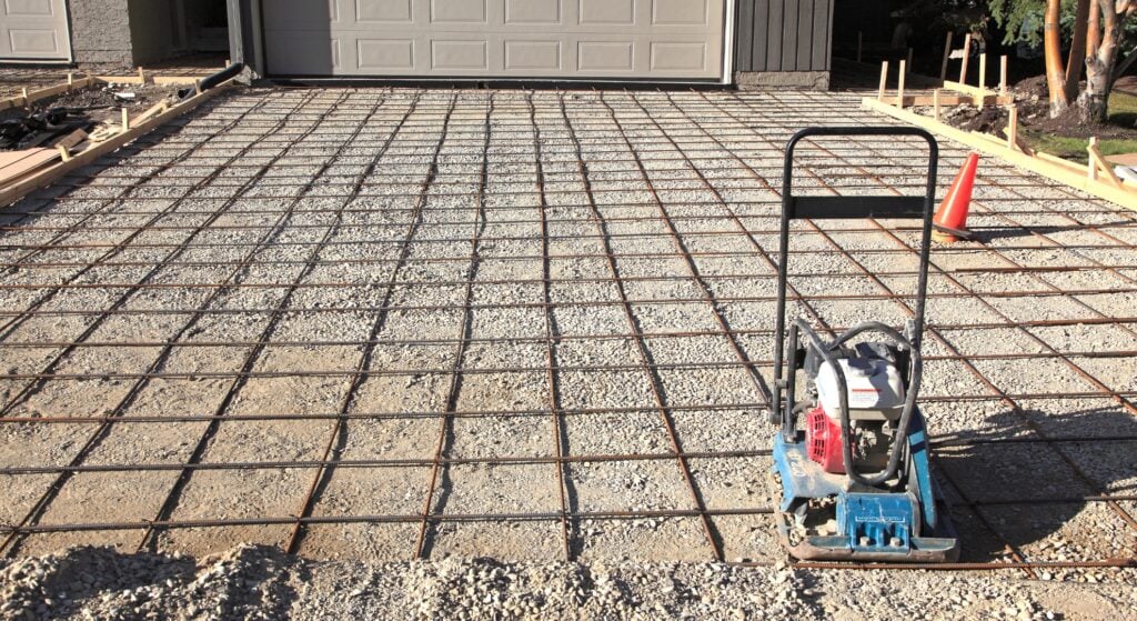 Reinforced driveway base with compactor before concreting