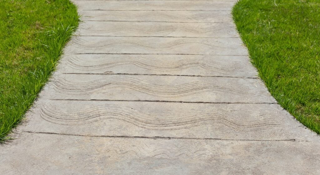 Concrete garden path bordered by green grass