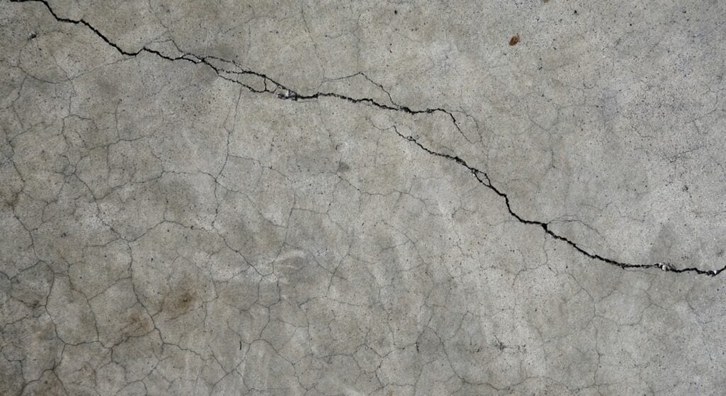 A damaged concrete surface showing deep cracks