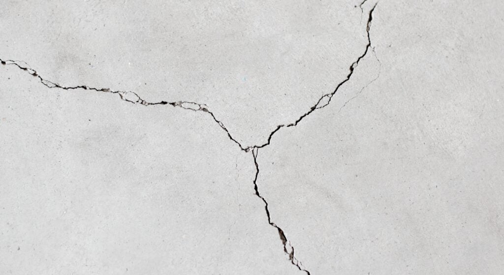 A weathered concrete surface with several large, branching cracks.
