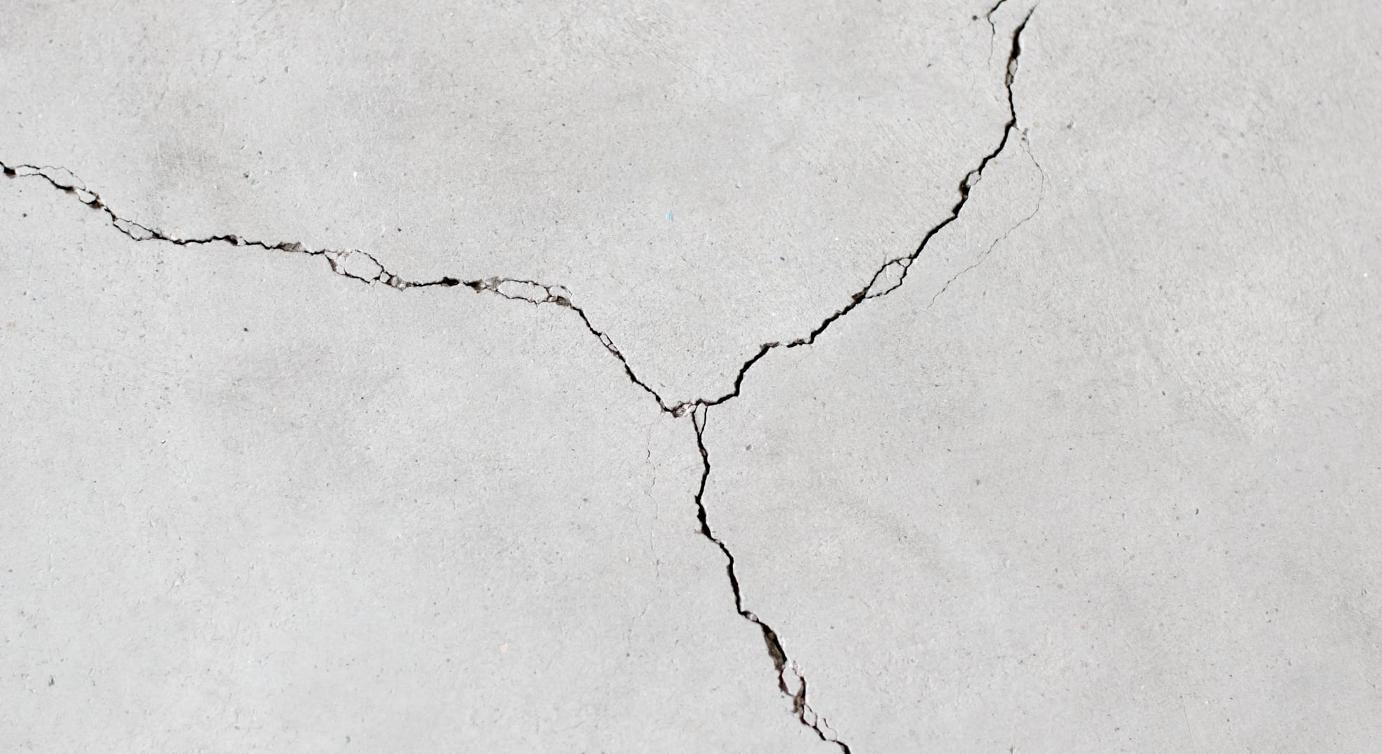 A weathered concrete surface with several large, branching cracks.