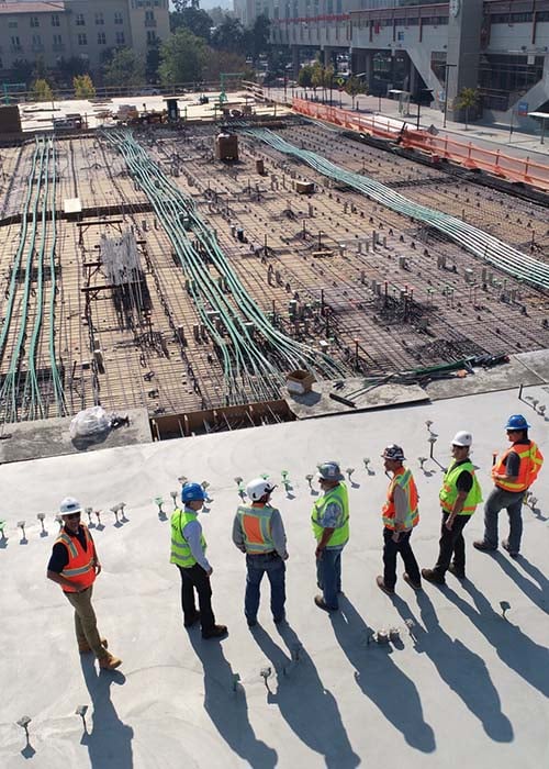Construction workers inspecting large building foundation site
