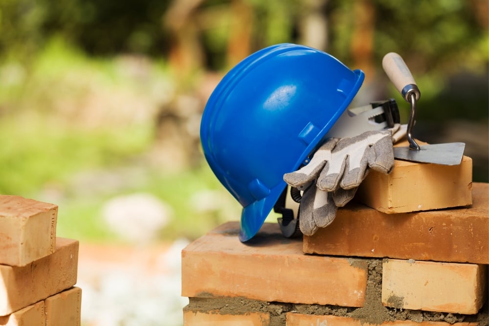 Blue hard hat, gloves and trowel on bricks