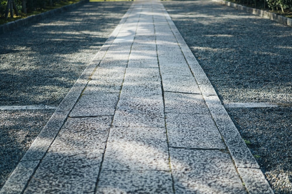 A straight walkway made of rectangular stone pavers stretching into the distance.