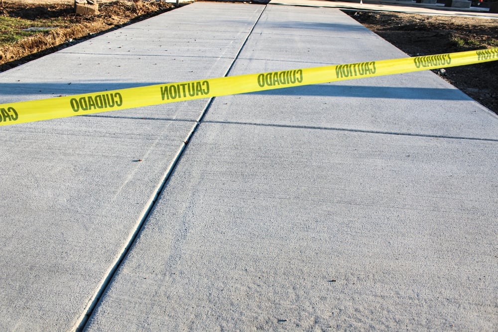 A newly poured grey concrete driveway or sidewalk with control joints.