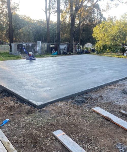 Freshly poured concrete slab in rural backyard setting