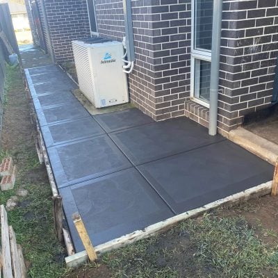 Fresh concrete pathway beside brick house exterior