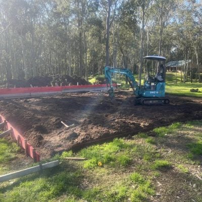 Mini excavator preparing house slab in bushland clearing