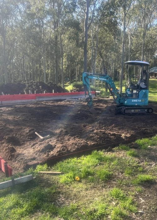 Mini excavator preparing house slab in bushland clearing