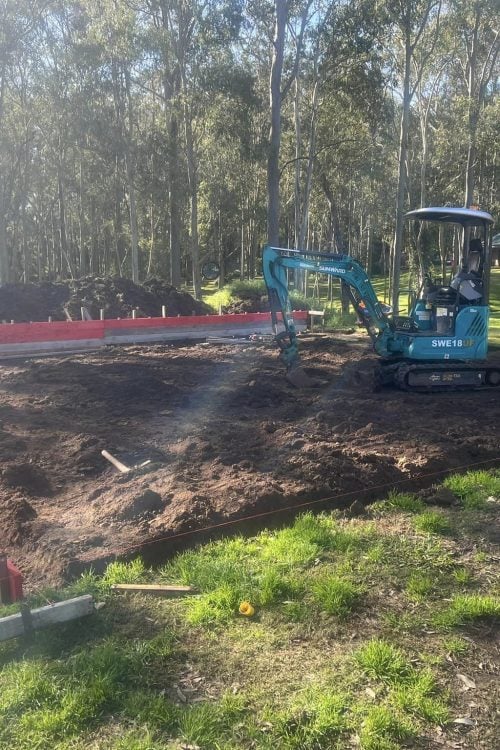 Mini excavator preparing house slab in bushland clearing