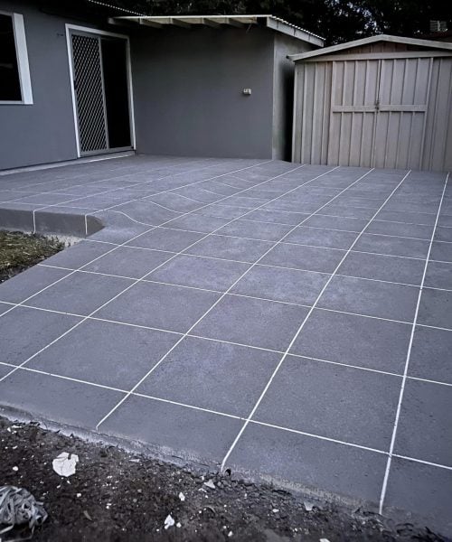 Newly tiled grey backyard patio with garden shed