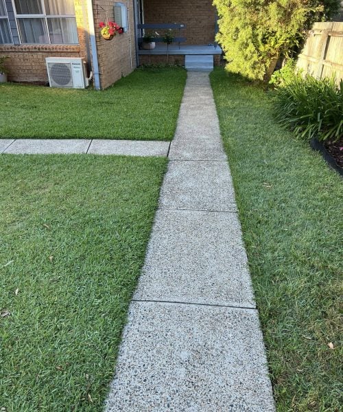 Concrete path through lawn to brick house porch