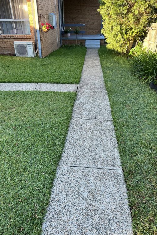 Concrete path through lawn to brick house porch