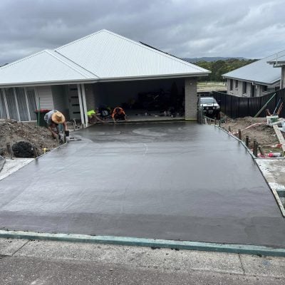 Workers smoothing freshly poured concrete driveway at house