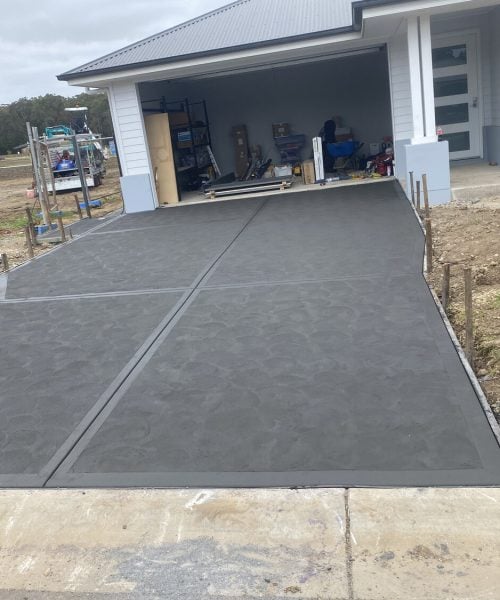 Newly poured concrete driveway leading to open garage