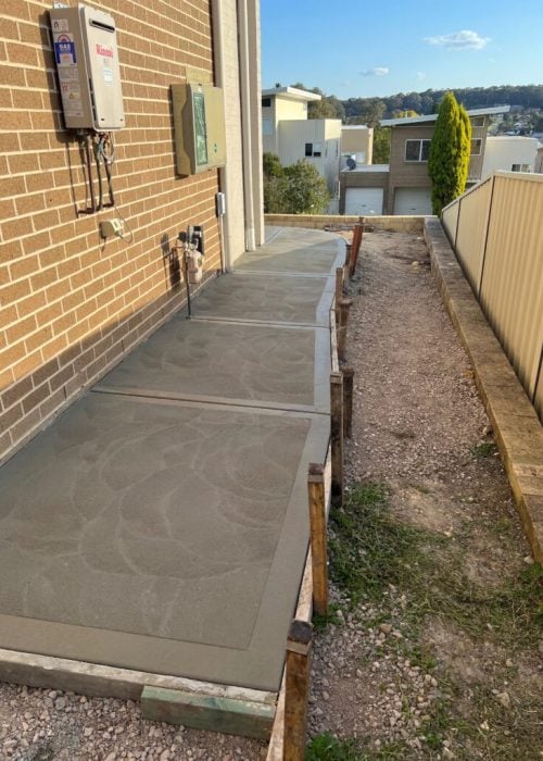 New concrete path beside brick house exterior